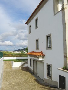 Vista lateral da casa, onde se pode apreciar as janelas, a porta, o portão da garagem, os esquinais, a cornija da cobertura do portão da garagem e as escadas, todos produzidos com granito da Sopedra.