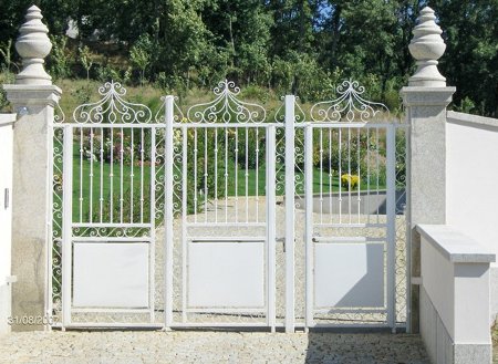 Portão de entrada ladeado por colunas de granito coroadas com pinha decorativa, também em granito